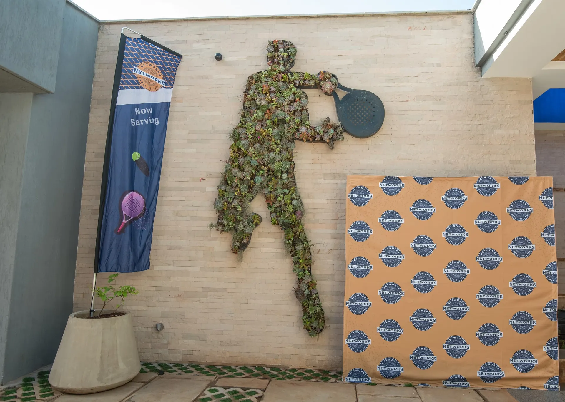 A topiary padel player set into the entrance wall.